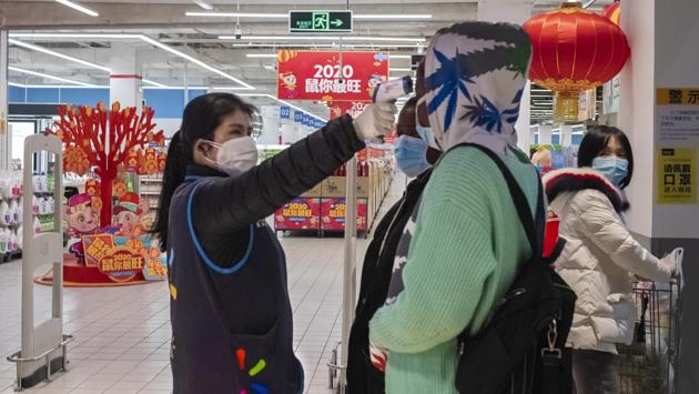 A worker takes the temperature of a customer at the entrance of a Walmart store in Wuhan. Arek and Jenina Rataj were starting a new life in the Chinese industrial center of Wuhan when a viral outbreak spread across the city of 11 million. (Arek Rataj / AP)