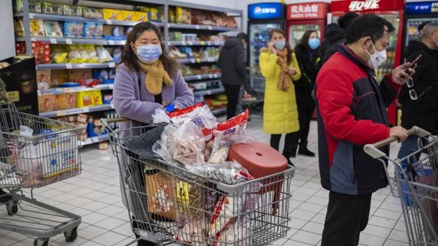 Shoppers wear face masks as they line up at a grocery store in Wuhan. Almost immediately, the metropolis teeming with Lunar New Year holiday revelry turned quiet. The couple, who have been married for five years, bought face masks for protection and kept to their apartment on the campus of Jianghan University, where Poland native Arek had recently taken a position teaching visual communication. (Arek Rataj / AP)