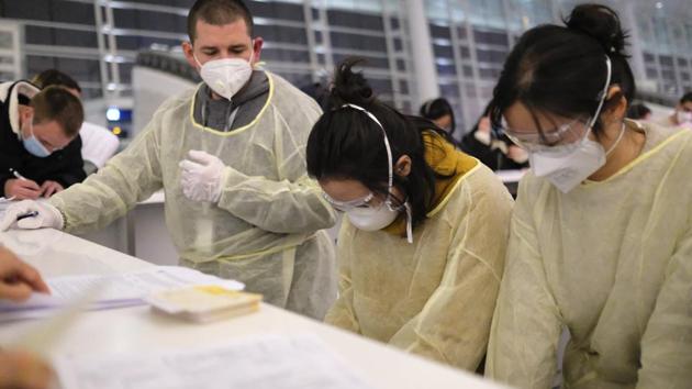 People wear face masks as they fill out immigration paperwork at Wuhan Tianhe International Airport. Staff at the terminal wore yellow hazmat suits, rubber gloves and goggles. A large group of Indian citizens were there, also being evacuated. One Chinese staffer told Arek that he was worried evacuating people would spread the disease outside of China. (Arek Rataj / AP)