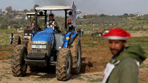 A Palestinian farmer uses a tractor to plow a field. Under the ICRC project, launched in 2015, members of the Hamas-led Interior Ministry have cleared unexploded ordnance and other war material from 40 percent of the 2,500 acres (1,012 hectares) that make up the borderlands in that tract. (Ibraheem Abu Mustafa / REUTERS)