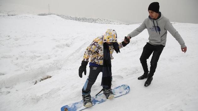 A member of the minority Hazara ethnic group, tries snowboarding with a trainer on the snow-covered hillside known as Kohe Koregh. (Rahmat Gul / AP)