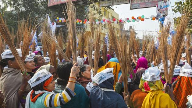 AAP volunteers hold brooms during an election campaign ahead of the forthcoming State Assembly elections, at Model Town. In the course of its outreach to voters, the AAP focused on its local governance record——and claimed to have improved government schools, public health facilities, electricity and water supply at subsidised rates, among other issues. (Shahbaz Khan / PTI)