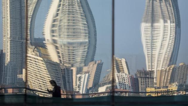 People walk against the reflection of buildings at Parel in Mumbai. (Aalok Soni / HT Photo)