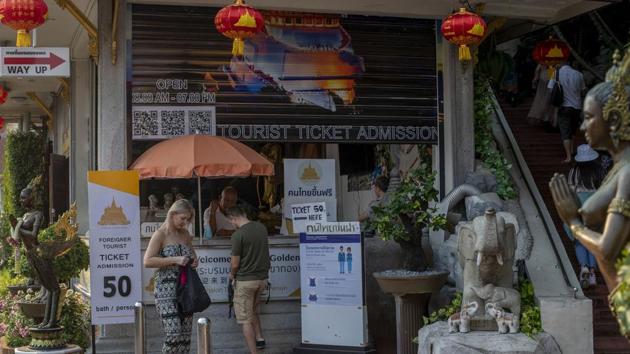 Tourists gather around a ticket counter to visit a Buddhist shrine, popular among tourists in Bangkok, Thailand. Asian nations have profited handsomely from the impressive growth in tourists from China over the past decade, but the spectre of a rapidly spreading virus has raised concerns over industry prospects. (Gemunu Amarasinghe / AP)