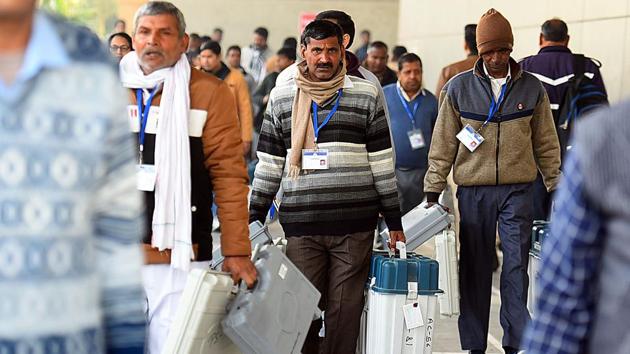 Polling officials carry EVM machines ahead of the 2020 Delhi assembly elections at Akshardham Sports Complex. (Raj K Raj / HT Photo)
