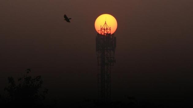 The sun rises behind a mobile communications tower on a cold winter morning in Gurugram. (Yogendra Kumar / HT Photo)