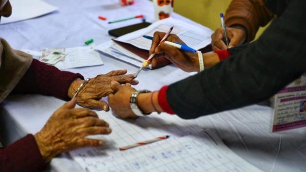 An elderly voter has their finger marked with indelible ink before proceeding to cast a vote at Sector 10 Dwarka, New Delhi. A total of 13,751 polling booths have been set up across 2,689 locations in the national capital. (Vipin Kumar / HT Photo)