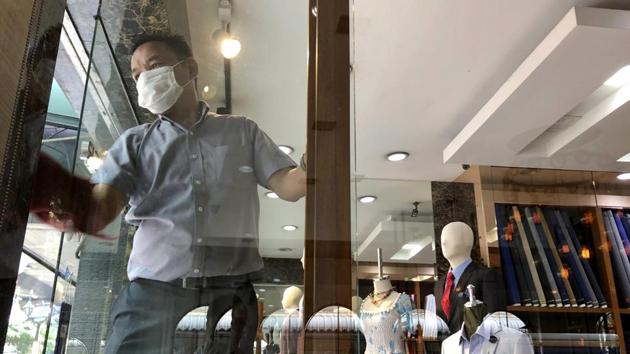 A tailor in a face mask wipes down his glass doors with disinfectant as he waits for customers in a normally busy tourist area in Bangkok. Using the SARS epidemic as a reference point, Wan noted an initial sharp decline in China’s GDP growth was largely offset by higher growth in the following two quarters, resulting in about 10% annual growth, reported AP. (Wally Santana / AP)