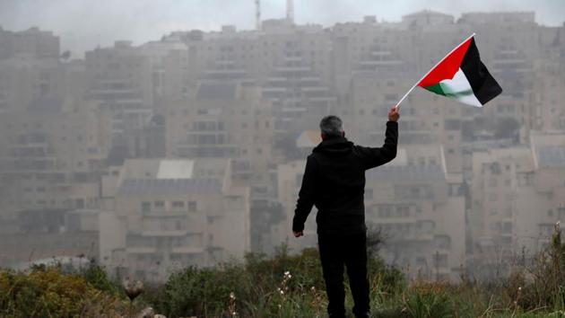 A demonstrator holds a Palestinian flag as the Jewish settlement of Modiin is seen in the background, during a protest against the U.S. President Donald Trump's Middle East peace plan, in the village of Bilin in the Israeli-occupied West Bank February 7, 2020.(REUTERS) A demonstrator holds a Palestinian flag as the Jewish settlement of Modiin is seen in the background, during a protest against the U.S. President Donald Trump's Middle East peace plan, in the village of Bilin in the Israeli-occupied West Bank February 7, 2020.(REUTERS)