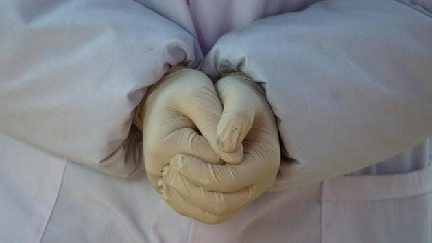 A nurse wearing rubber gloves folds her hands at a checkpoint at China.(REUTERS)