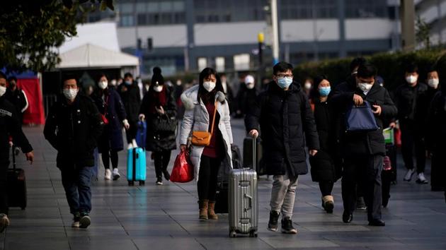 Passengers wearing masks walk at the Shanghai railway station in China.(Reuters image)