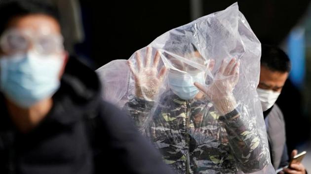 A passenger wearing a mask and covered with a plastic bag walks outside the Shanghai railway station in Shanghai, China, as the country is hit by an outbreak of a new coronavirus, February 9, 2020. (REUTERS) A passenger wearing a mask and covered with a plastic bag walks outside the Shanghai railway station in Shanghai, China, as the country is hit by an outbreak of a new coronavirus, February 9, 2020. (REUTERS)
