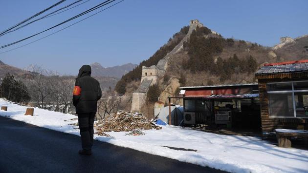 A security guard walks past a closed restaurant opposite a section of the Great Wall of China at Huanghuacheng, north of Beijing. At the Marco Polo Hotel, one of the few in Wuhan that had not closed it doors, there were compulsory masks, temperature checks and no restaurant. With no one at the reception, there was a heavy silence that jarred with the festive decorations all around. (Greg Baker / AFP)