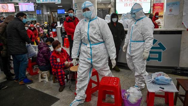 Medical staff members working to stop the spread of the virus seen next to patients waiting for medical attention at the Wuhan Red Cross Hospital. Hours before the Lunar New Year, shops were closed and there was a ghostly silence hanging over the city. The police and security services—usually prominent on Chinese city streets—were conspicuous by their absence. (Hector Retamal / AFP)