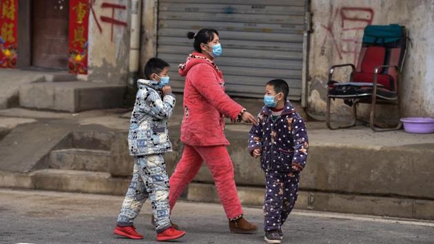 Members of a family walk in a neighbourhood on the outskirts of Wuhan. The Guiyan temple, normally packed with hundreds of thousands of people welcoming in the New Year, was closed on New Year’s Day. “No-one is allowed inside in order to prevent the virus spreading,” a uniformed man—who was not wearing the compulsory mask—told AFP. (Hector Retamal / AFP)
