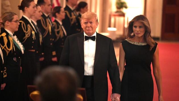 US President Donald Trump holds hands with first lady Melania Trump as they arrive to host the Governors Ball in the East Room of the White House, Washington.(REUTERS)