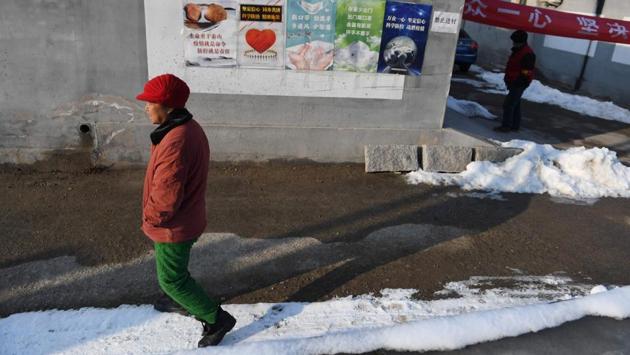 A woman walks past posters advising residents on how to prevent the spread of the novel coronavirus in Heishanzhai village, north of Beijing. As the virus claims more lives and infects more people every day, it is also taking a toll on the country's small businesses that rely on spending from China's growing middle-class. (Greg Baker / AFP)