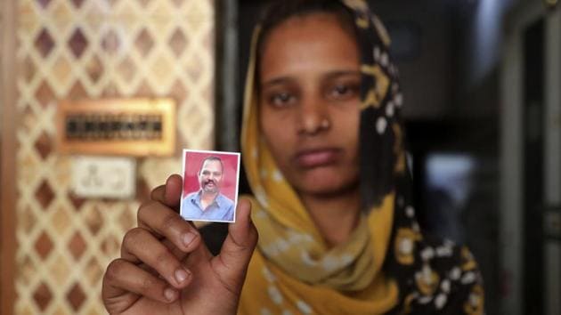 Zeel Makwana holds up a photograph of her father Bhalabhai Makwana, one of the victims of Saturday's fire. One victim, Dayabhai Makwana, 43, made it out alive, but went back in to rescue co-workers and perished. “I wish he hadn’t gone back to save his colleagues,” said his grieving brother Dhanabai Makwana. He said more than 30 workers were in the factory at the time of the blaze. (Ajit Solanki / AP)