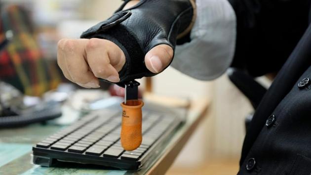 Shinya Ando types with a tool attached to his glove. Progress has been made, with accessibility improving in Tokyo and legislation setting quotas for hiring people with disabilities in government. But rights activists say more must be done: the government was earlier forced to apologise for padding its disability hiring data, after regularly failing to meet its own quotas. (Kazuhiro Nogi / AFP)