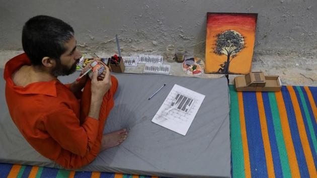Abed El-Hamed Atiya, an Iraqi prisoner, suspected of being part of the Islamic State, sits next to a picture he drew inside a prison in Hasaka. Atiya is kept apart from other prisoners, some of whom strongly object to his art. Conditions in the prison near Hasaka, which used to be a school before being transformed to cope with the influx of captives, were markedly worse than those at the central jail. (Goran Tomasevic / REUTERS)