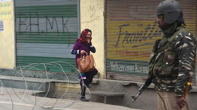A woman crosses barbed concertina wire as a soldier stands guard during restrictions in downtown area of Srinagar, Jammu and Kashmir. (Waseem Andrabi / Hindustan Times) A woman crosses barbed concertina wire as a soldier stands guard during restrictions in downtown area of Srinagar, Jammu and Kashmir. (Waseem Andrabi / Hindustan Times)