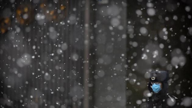 A security guard wears a face mask as he stands during a snowfall in Beijing, China. (Mark Schiefelbein / AP)