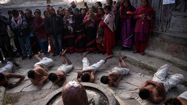 Hindu devotees offer prayers by rolling on the ground after performing a bathing ritual on the last day of the month-long Swasthani Festival at the Hanumante River in Bhaktapur on the outskirts of Kathmandu, Nepal. (Prakash Mathema / AFP)