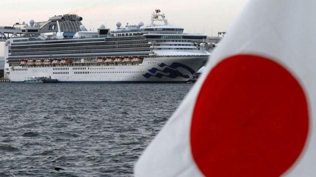 The cruise ship Diamond Princess is pictured beside a Japanese flag as it lies at anchor while workers and officers prepare to transfer passengers who tested positive for coronavirus.(REUTERS)