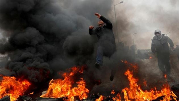 A Palestinian demonstrator jumps over burning tires during a protest against US President Donald Trump's Middle East peace plan and in support of President Mahmoud Abbas, near the Jewish settlement of Beit El in the Israeli-occupied West Bank. (Mohamad Torokman / REUTERS)