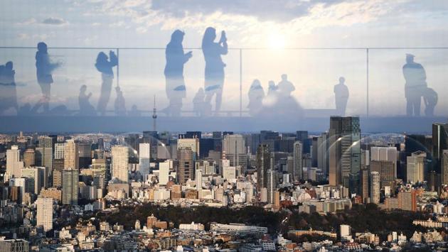 Reflections of people are seen on glass from a rooftop viewing area showing Tokyo's east side, in Japan. (Charly Triballeau / AFP)