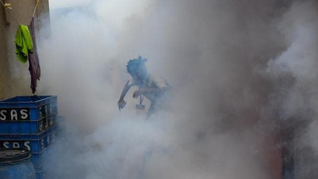 A school girl is seen engulfed in smoke as a municipal worker fumigates a residential area at Versova Koliwada, in Mumbai. (Shashi S Kashyap / HT Photo)