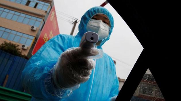 A medical worker holds a thermometer to check a passenger's temperature at a checkpoint in Susong County, Anhui province. “While the Chinese authorities are doing their best to prevent the spread of the coronavirus, the fairly drastic measures they have implemented to date would appear to have been too little, too late,” Kamradt-Scott said. (Thomas Peter / REUTERS)