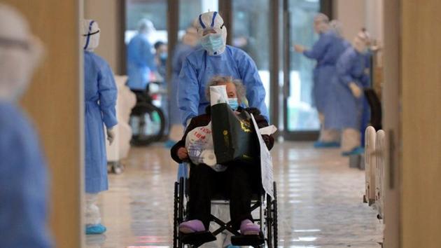 A medical worker moves a novel coronavirus patient in a wheelchair at a hospital in Wuhan. In Hubei province, where Wuhan is located, 1,933 new cases and 100 new deaths were reported—the lowest daily death count since February 11. (China Daily via REUTERS)