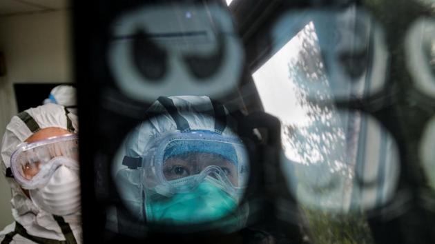 Medical workers in protective suits check a CT scan image of a patient at a community health service centre in Wuhan. The Chinese health commission vice minister, Zeng Yixin, said 1,716 health workers had been infected and six had died as of Tuesday last week, with the number of infected staff rising. (China Daily via REUTERS)