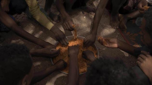 During the wait to cross, smugglers brought out large pots of spaghetti and barrels of water. Young men and women washed themselves in nearby wells. Others sat in the shade of the scrawny, twisted acacia trees. At night, AP witnessed a daily smuggling routine: small lights flashing in the darkness. More than 100 men and women, boys and girls ordered to sit in silence on the beach. (Nariman El-Mofty / AP)