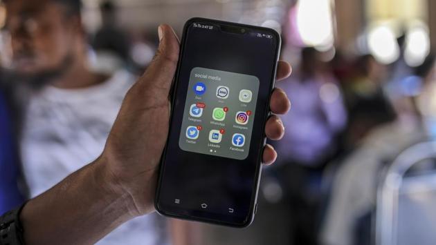 A passenger displays application icons for various social media platforms on a smartphone for a photograph while travelling by a train in Mumbai. The rules cover all social media and messaging apps with more than 5 lakh users. India, with 130 crore people, has about 50 crore internet users. It isn’t clear whether the identities of foreign users would be subject to the Indian government’s inquiries. (Dhiraj Singh / Bloomberg)