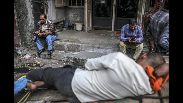 People use smartphones while sitting on steps in Mumbai. Facebook, YouTube, Twitter and TikTok will have to reveal users' identities if government agencies ask them to, according to the new rules for social media companies and messaging apps expected to be published later this month. (Dhiraj Singh / Bloomberg)