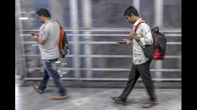 Pedestrians use smartphones while walking along a sidewalk in Mumbai. WhatsApp refused a request from the government to reveal the origins of the rumours, citing its promise of privacy and end-to-end encryption for its 40 crore Indian users. It instead offered to fund research into preventing the spread of fake news and mounted a public education campaign in the country, its biggest global market. (Dhiraj Singh / Bloomberg)