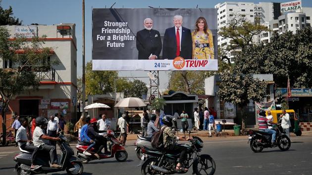 People ride their motorbikes past a hoarding with the images PM Modi, US President Donald Trump and first lady Melania Trump. Security-related costs, with more than 12,000 police officers expected to be deployed, will account for almost half the expense, said the officials, who declined to be named as they are not authorised to speak publicly about the visit. (Amit Dave / REUTERS)