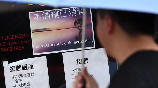 A passer-by looks at a sign from a Chinese restaurant stating it is disinfected daily, in Melbourne's Chinatown. Streets are notably quieter, face masks are commonplace and even a Lunar New Year dragon dance failed to bring in the crowds. Businesses report their earnings have dropped by more than half and they have been forced to cut staff hours dramatically, a situation echoed in Chinatowns across the world. (William West / AFP)