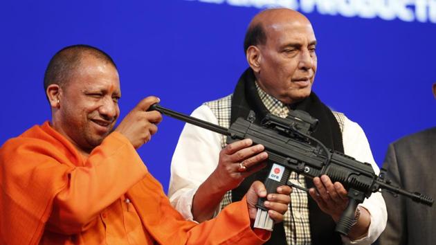 UP CM Yogi Adityanath looks at a model of the Joint Venture Protective Carbine, with Defence Minister Rajnath Singh standing beside him during DefExpo20 in Lucknow.(AP)