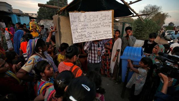 A placard hangs as residents gather to support Aswathy Jwala (not pictured, in Ahmedabad. Critics have said the wall was built to block the view of the slum area inhabited by more than 2,000 people. Mayor Bijal Patel said the wall was built “for security reasons” and not to conceal the slum, according to the AP. (Amit Dave / REUTERS)