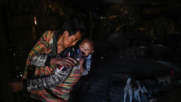 A man takes care of his child as his wife carries wood for the overnight ceremony. Like most Naga, the Gongwang Bonyo are mainly subsistence farmers who clear and burn the steep slopes around them to plant paddy, maize and vegetables. The next season they move on, leaving the soil to recover for up to 10 years. (Ye Aung Thu / AFP)
