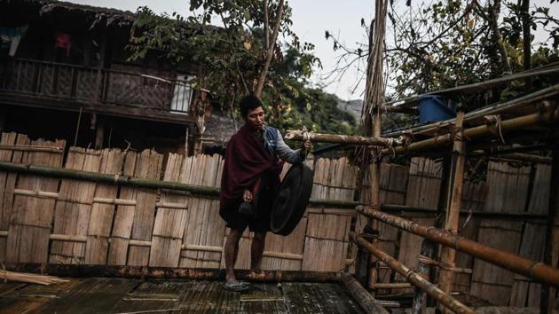 A man rings a gong as the day breaks after the ceremony. As the roosters crowed and the sun rose, youngsters were welcomed into the circle while the men prepared a freshly slain pig for the day’s feast. “We worry about losing our traditions. That’s why we teach them to our children,” said village head Maung Tar. (Ye Aung Thu / AFP)