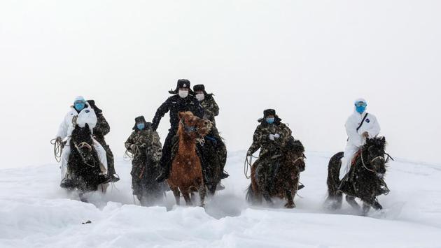 Police officers wearing protective face masks ride horses on their way to visit residents in remote areas in Altay, farwest China's Xinjiang region, to promote the awareness of the COVID-19 virus. (AFP)