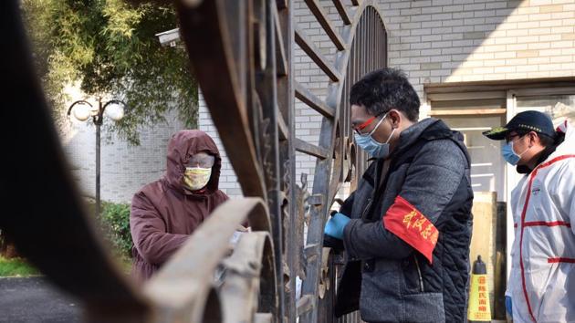 A volunteer brings a delivery to a woman in a locked down apartment complex in Wuhan in central China's Hubei Province, Friday, Feb. 21, 2020. (AP) A volunteer brings a delivery to a woman in a locked down apartment complex in Wuhan in central China's Hubei Province, Friday, Feb. 21, 2020. (AP)