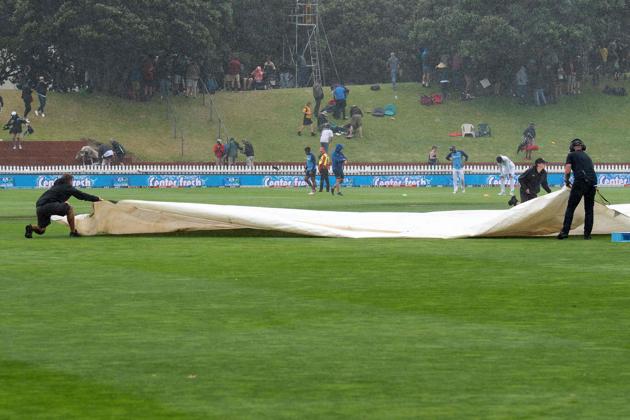 Grounds staff race to put the covers on the pitch as rain falls during day one of the first Test cricket match between New Zealand and India at the Basin Reserve in Wellington. (AFP)
