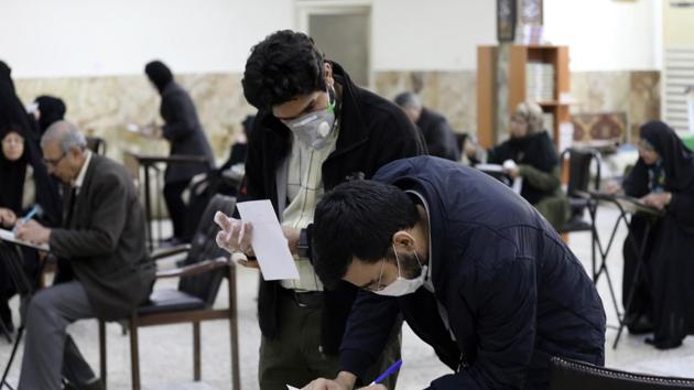 Voters with face masks fill out their ballots in the parliamentary elections at a polling station in Tehran, Iran, Friday, Feb. 21, 2020.(AP)
