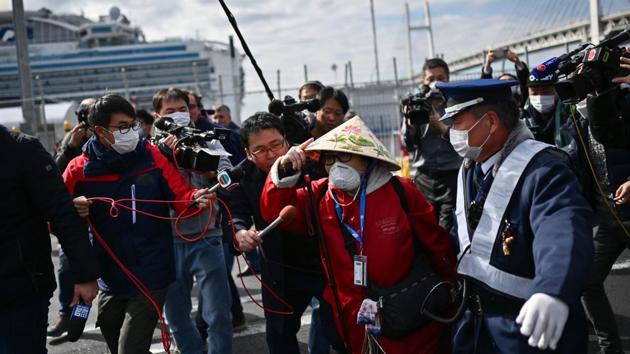 A passenger (C), among the first, leaves on foot after disembarking the Diamond Princess cruise ship in quarantine due to fears of the new COVID-19 coronavirus, at the Daikoku Pier Cruise Terminal in Yokohama, Japan. (Charly Triballeau / AFP)