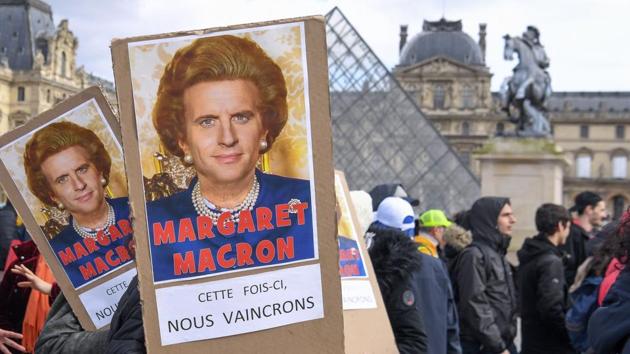 Protesters hold placards reading “Maragaret Macron, this time we will win” under a photomontage of late British Prime Minister Margaret Thatcher and French President Emmanuel Macron as they demonstrate in front of Paris’ Louvre Museum as part of a multi-sector strike against the French government's pensions overhaul. (Alain Jocard / AFP)